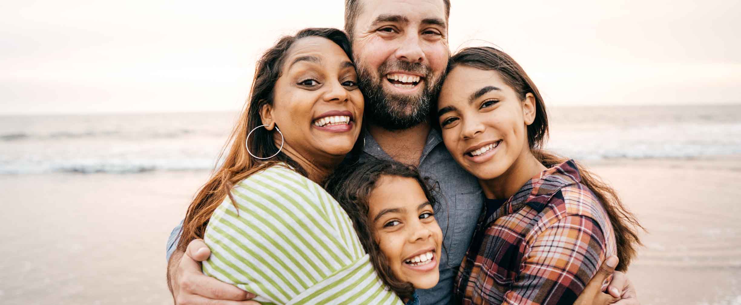 smiling parents hugging their two young daughters