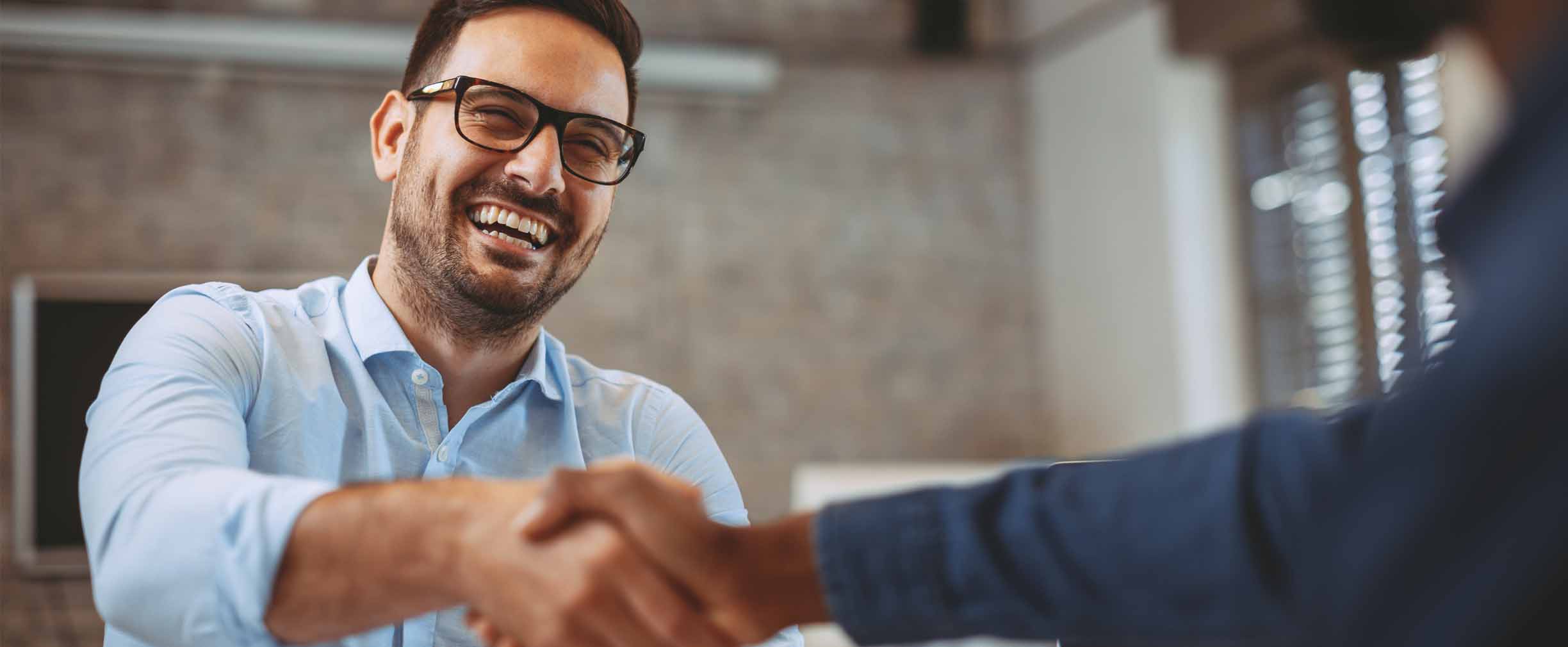 male young professional smiling and shaking hands with a colleague