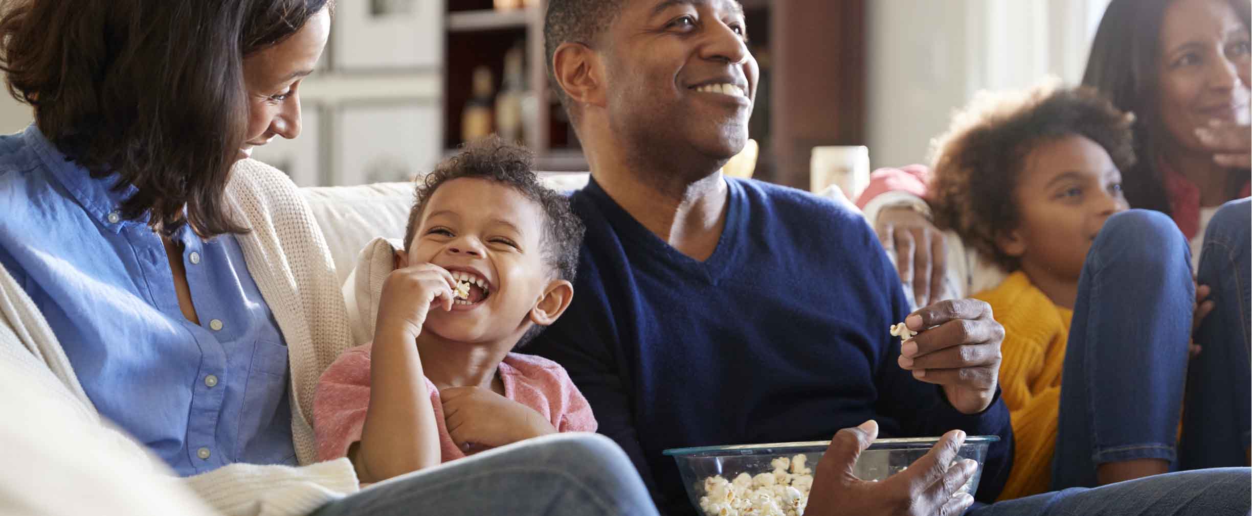 happy three generation family watching a movie and eating popcorn