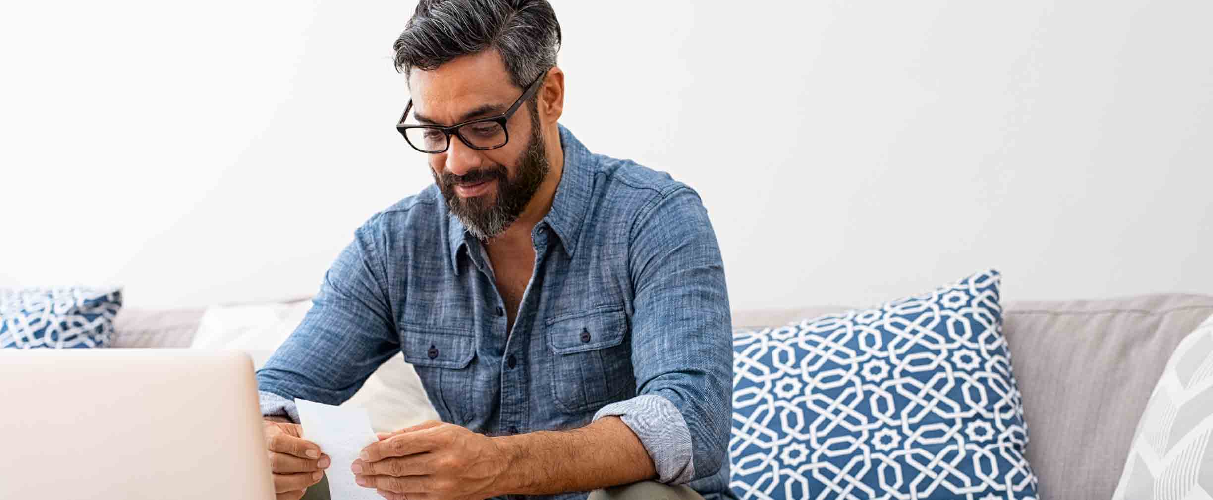 man reading bills on his couch