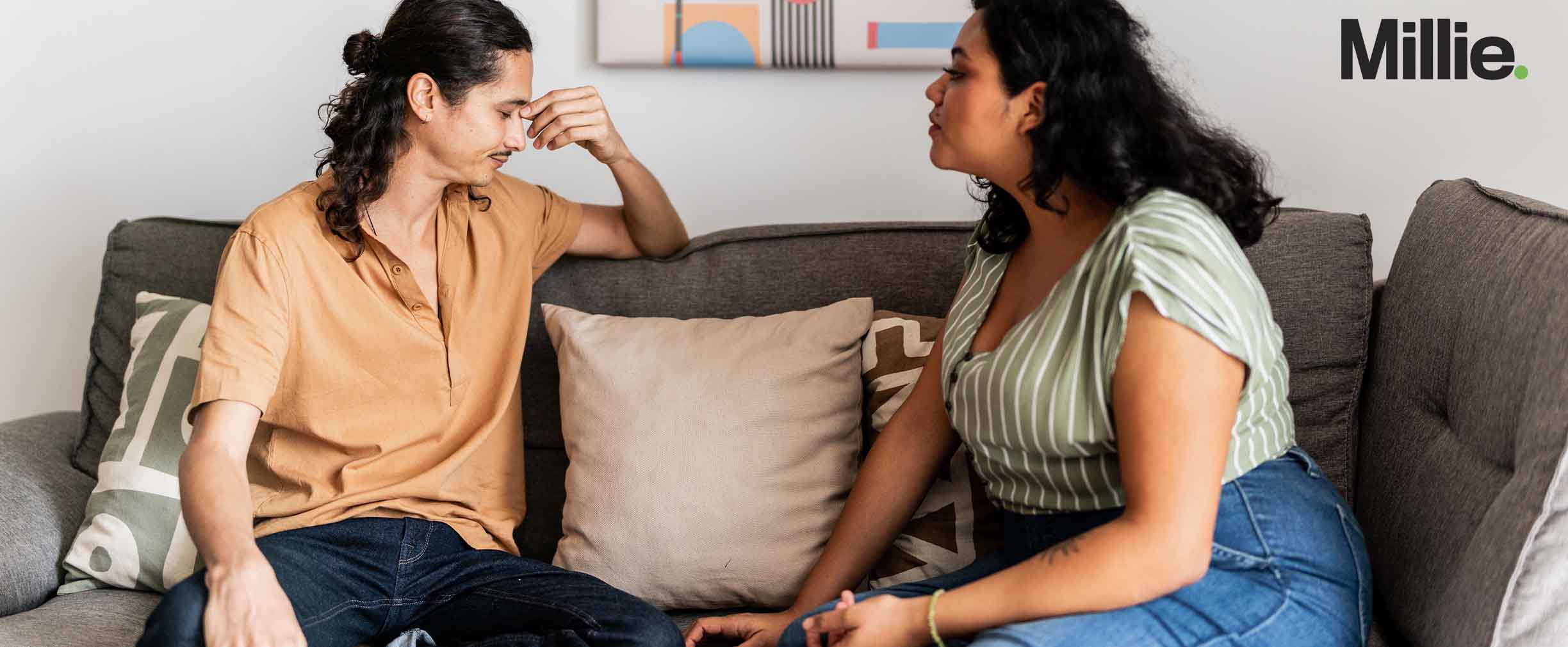 A frustrated couple sitting on a couch discussing debt.