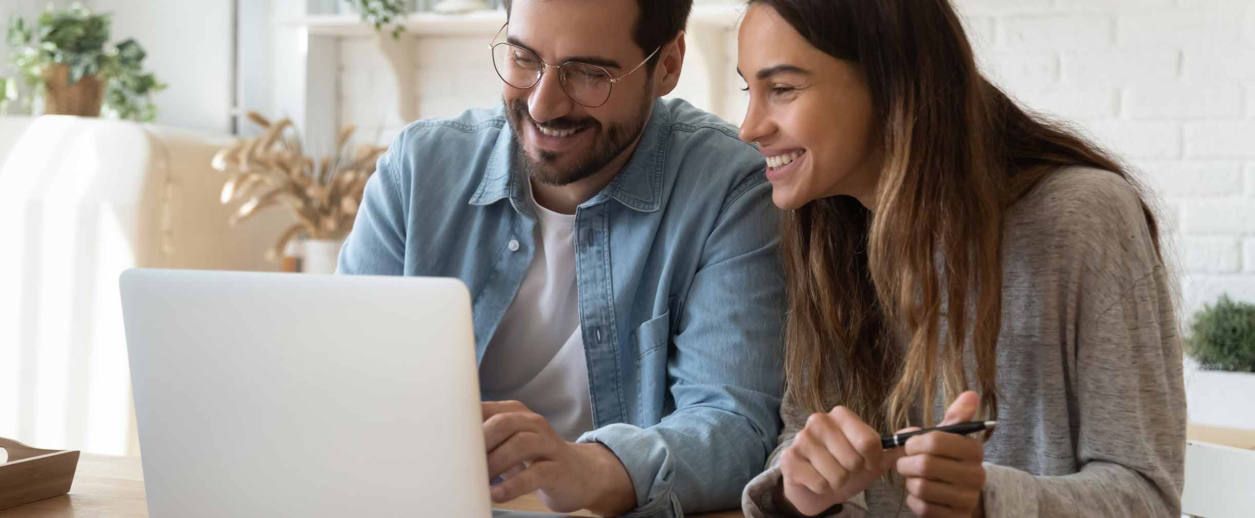 Happy young couple using laptop at home. 