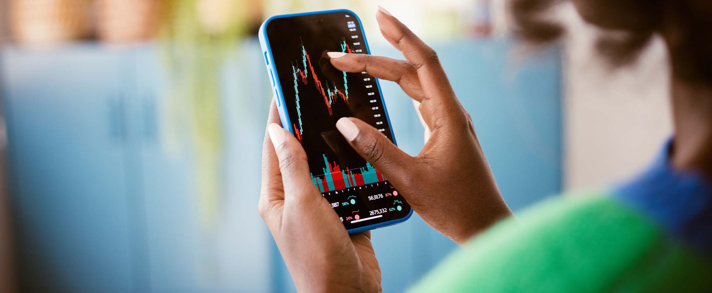 A close up photograph of a woman reviewing the fluctuating value of assets on her smartphone