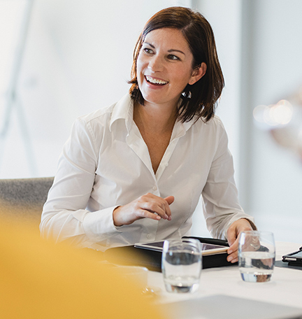 Businesswoman smiling at meeting table, listening, learning, success, happiness